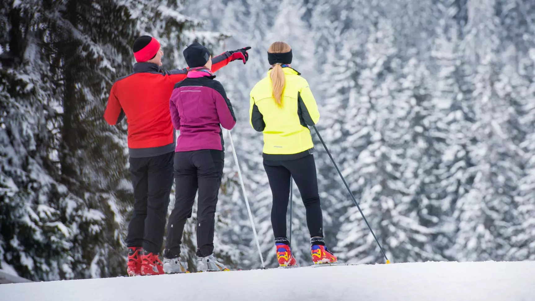Kolme hiihtäjää, yksi heistä osoittaa jotain tärkeää