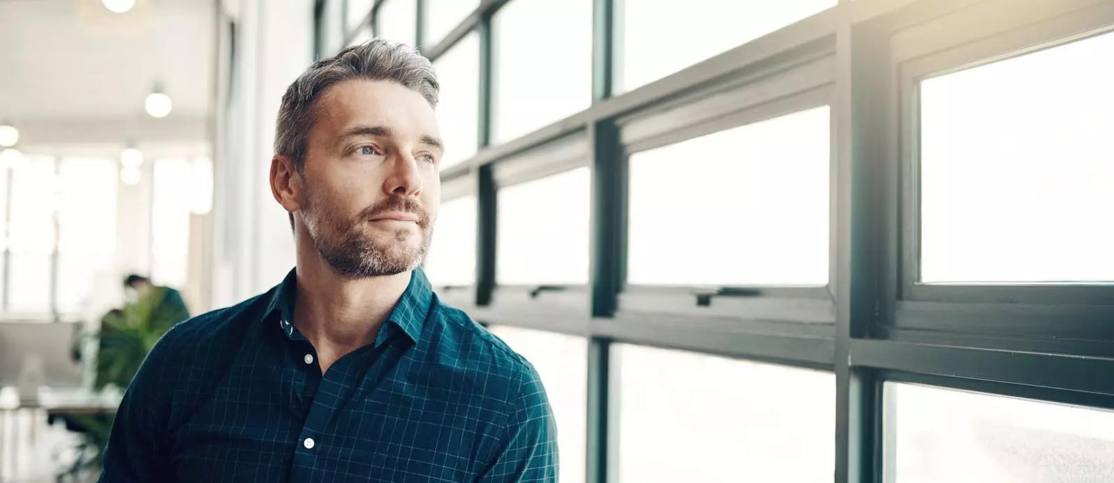 Mies katsoo miettiäänä ikkunasta