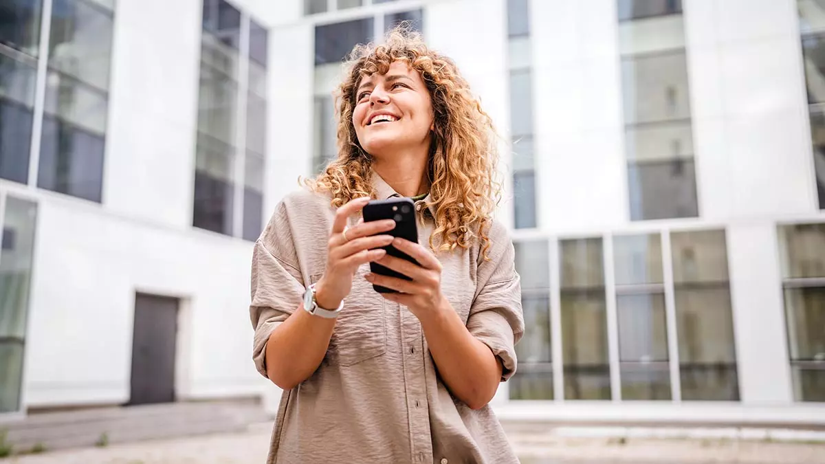 Iloinen nainen mobiililaite kadessa