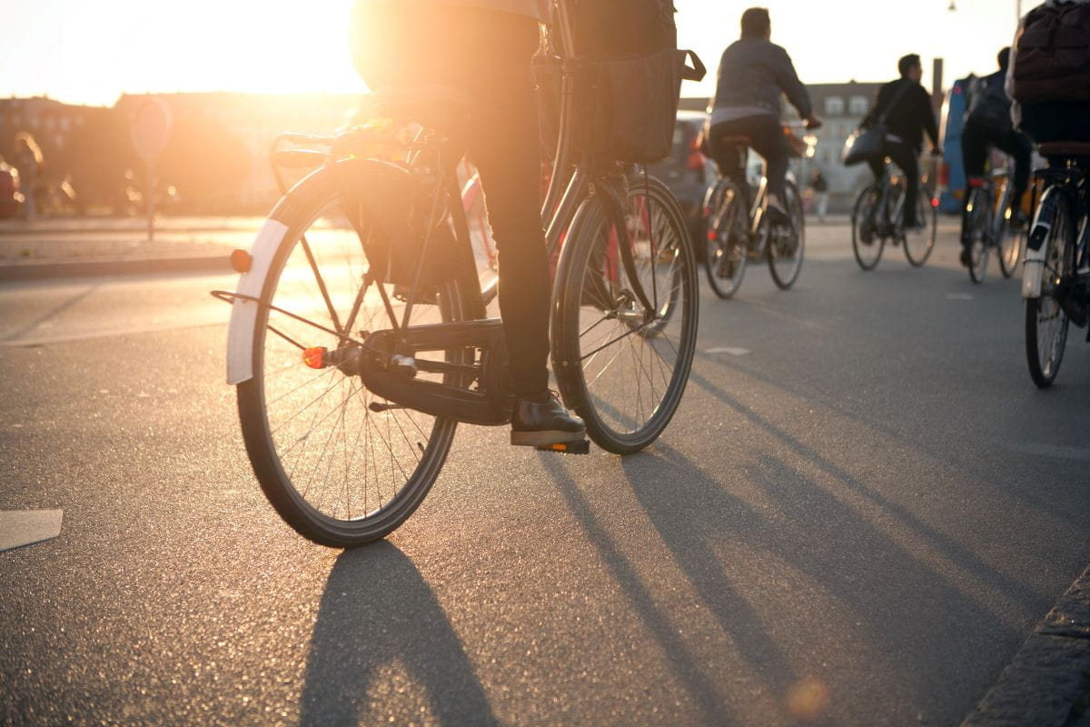 Joukko pyöräilijöitä pyöräilee auringon laskiessa