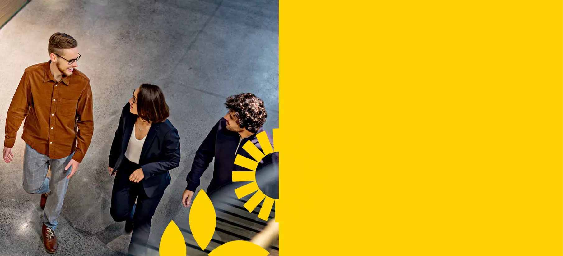 Kolme henkilöä kävelee ja keskustelee modernissa toimistossa