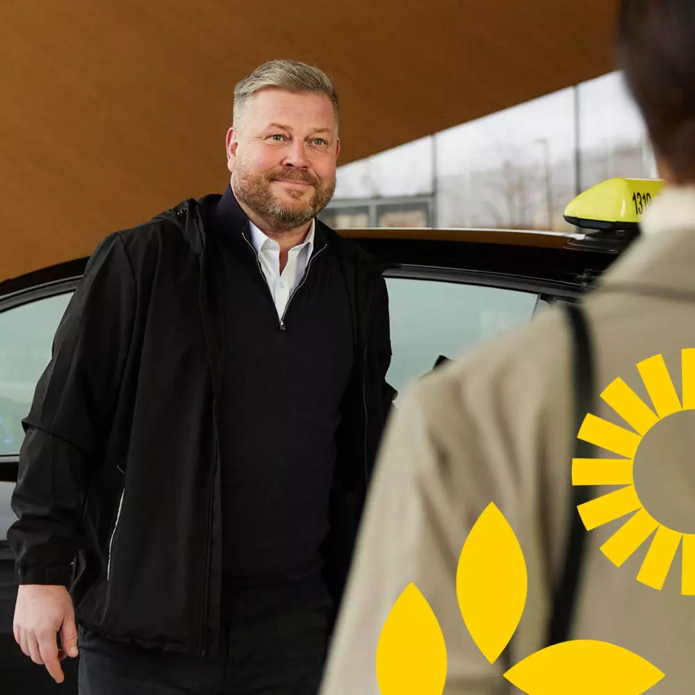 Taksiyrittäjä avaa taksin oven asiakkaalle