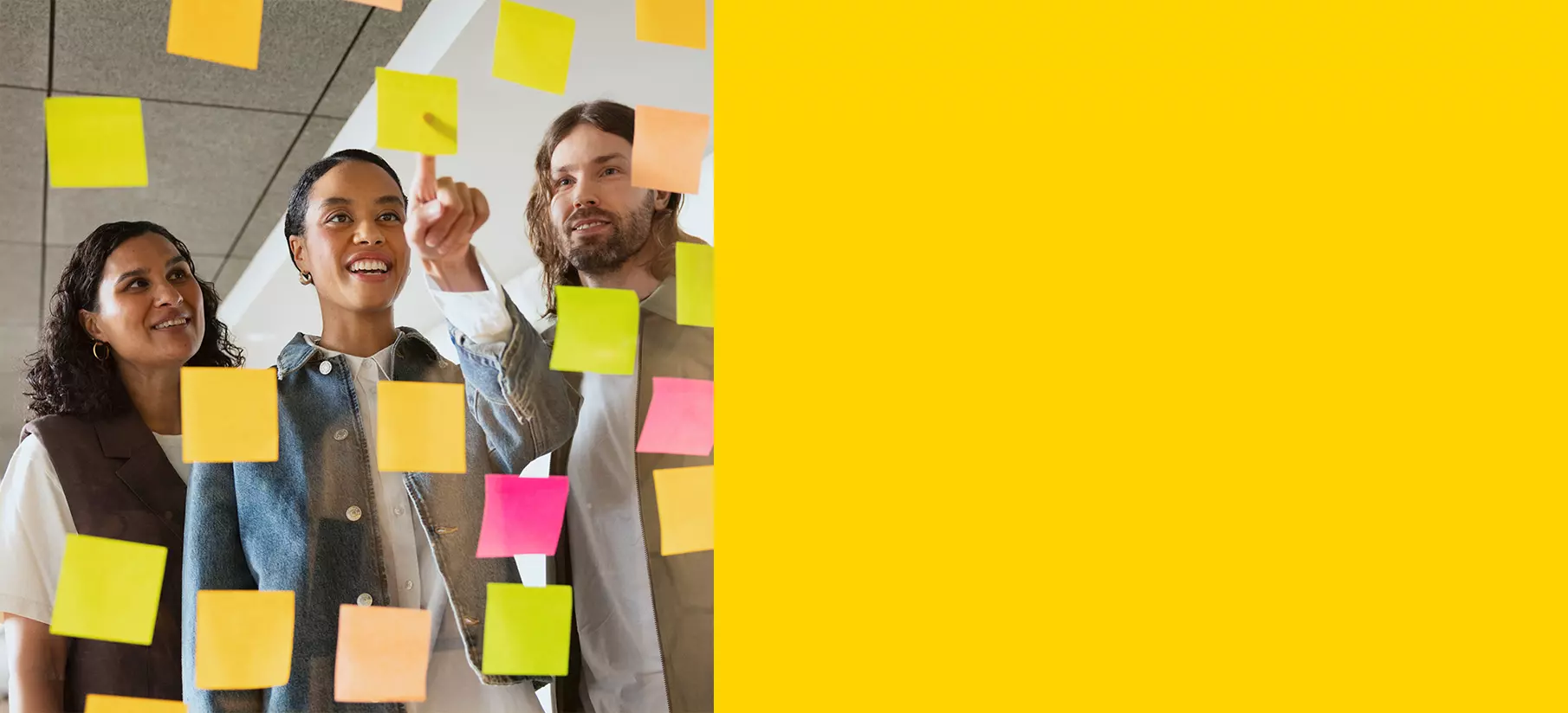 Three people are looking at post-it notes