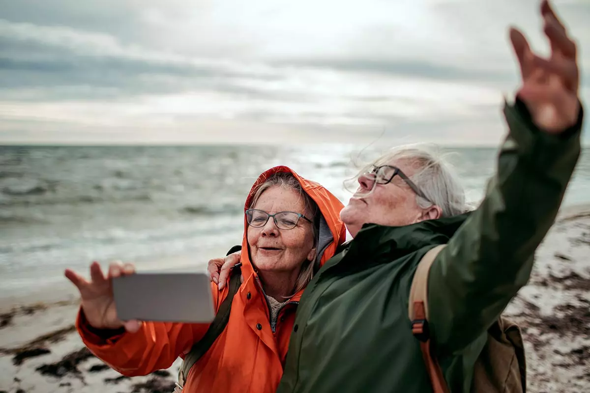 Vanha pariskunta ottaa selfie-kuvaa meren rannalla