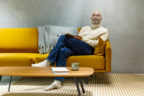 Mies istuu sohvalla kirja kädessä