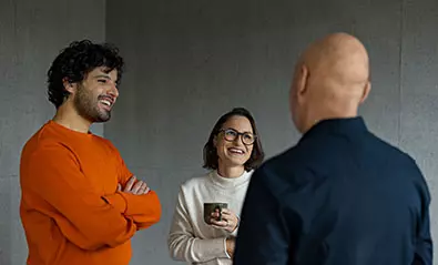 Kolme-henkiloa-keskustelee-kalju-henkilo-selin-kameraan