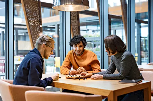 kolme-ihmista-poydan-aaressa-pelaamassa