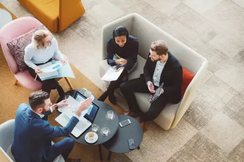 tyoporukka-keskustelee-istuen-poydan-ja-papereiden-aaressa