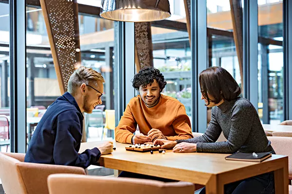 Tre personer spelar ett brädspel