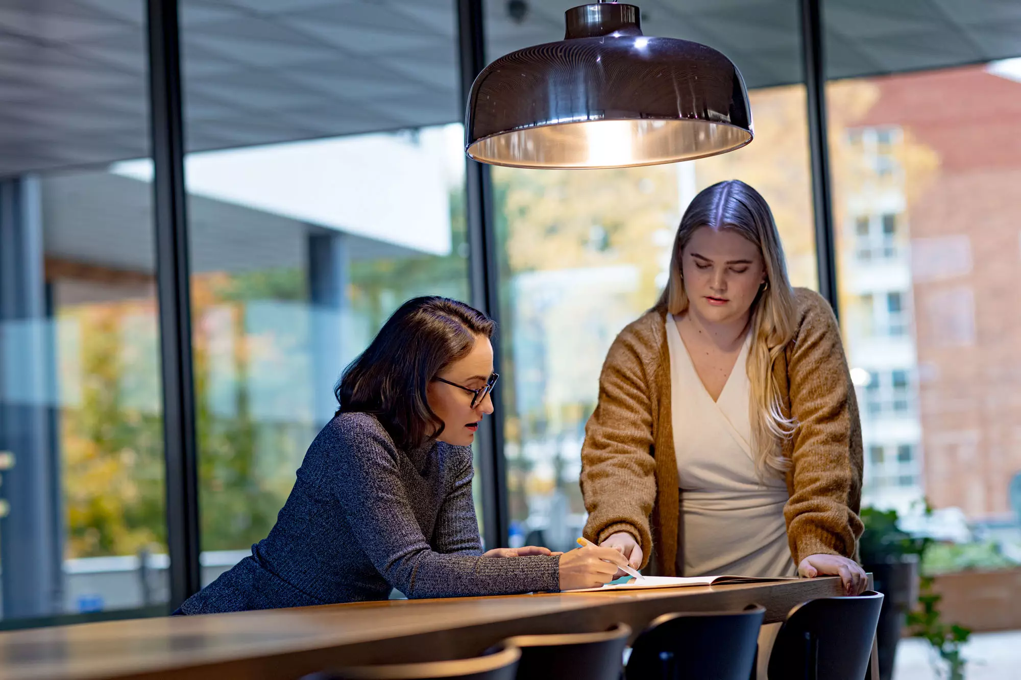 Kuva, jossa kaksi ihmistä tekevät töitä toimiston keittiössä