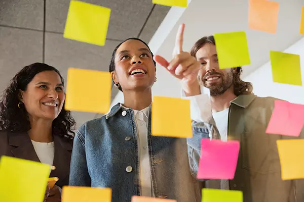 Tre personer tittar på post-it lappar
