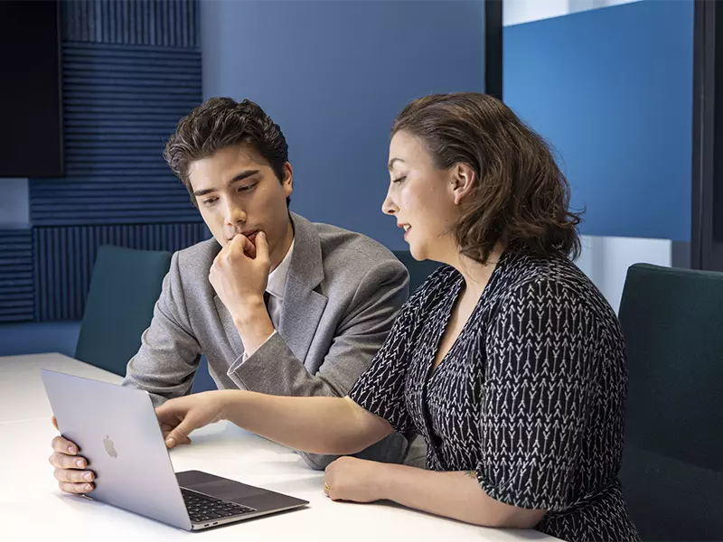 Two people are looking at a laptop