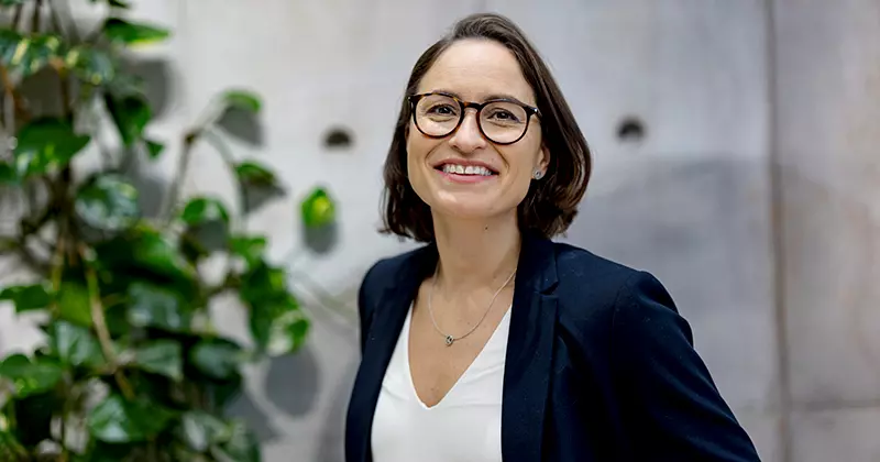 Hymyilevä nainen toimistolla – Siirrä TyEL-vakuutus Eloon helposti verkossa