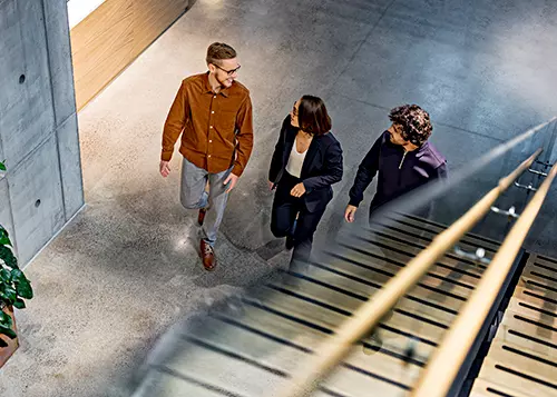 Three people are walking and talking in the office