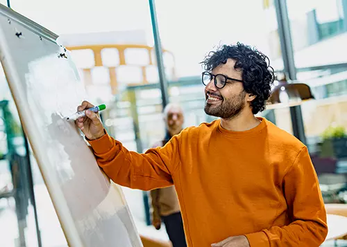 A man is writing on the whiteboard