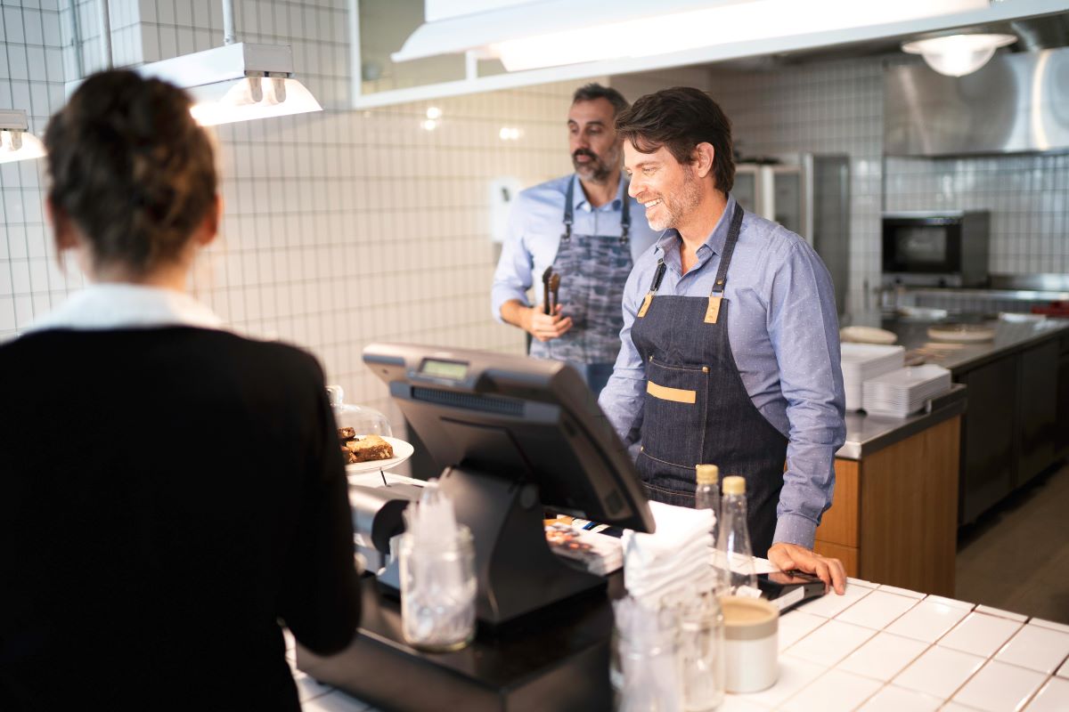 Ravintolan kassalla työntekijät ja asiakas