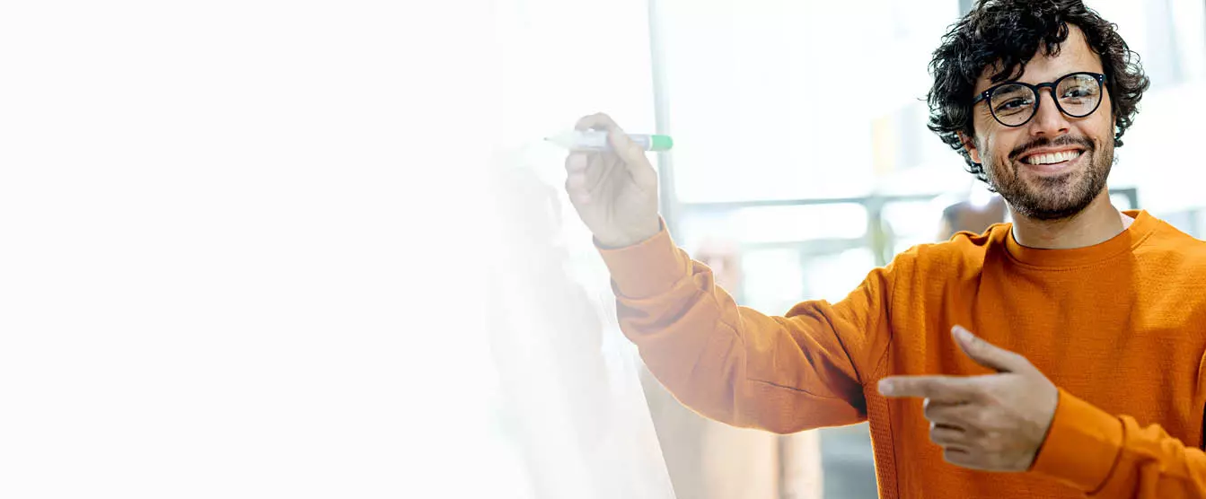 Hymyilevä mies kirjoittaa valkotaululle