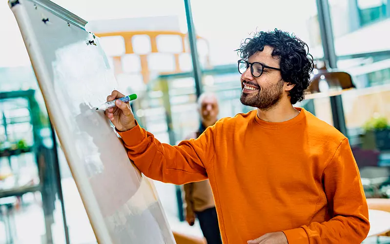 Mies kirjoittaa fläppitaululle